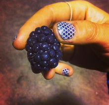 Load image into Gallery viewer, Hand holding a blackberry with patterned nail polish on a dark background