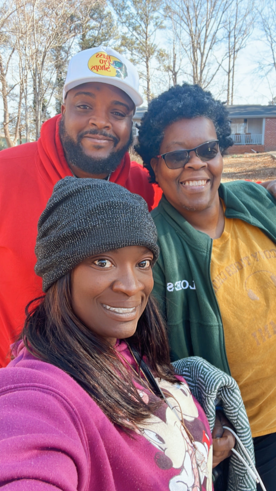 Three people smiling together outdoors.