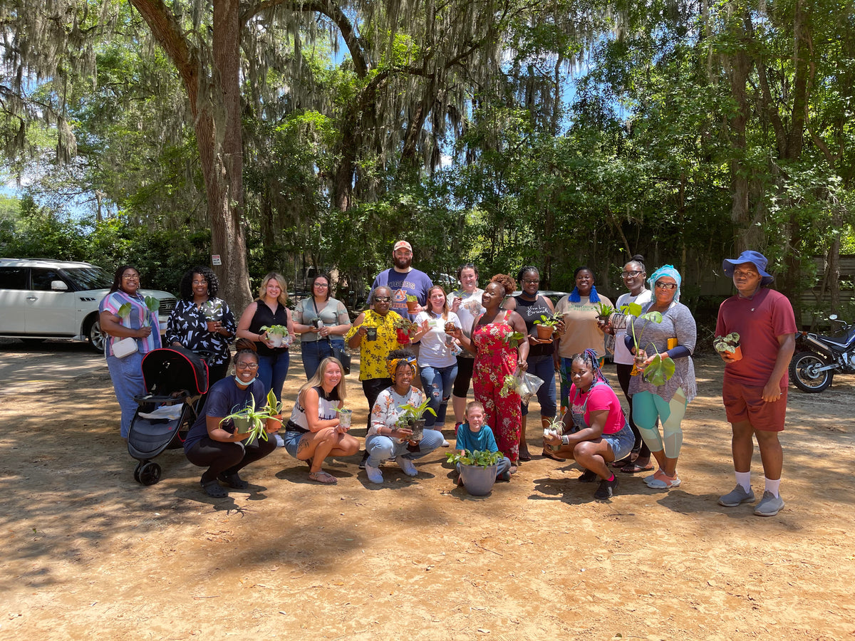A large group posing together outdoors beneath trees.