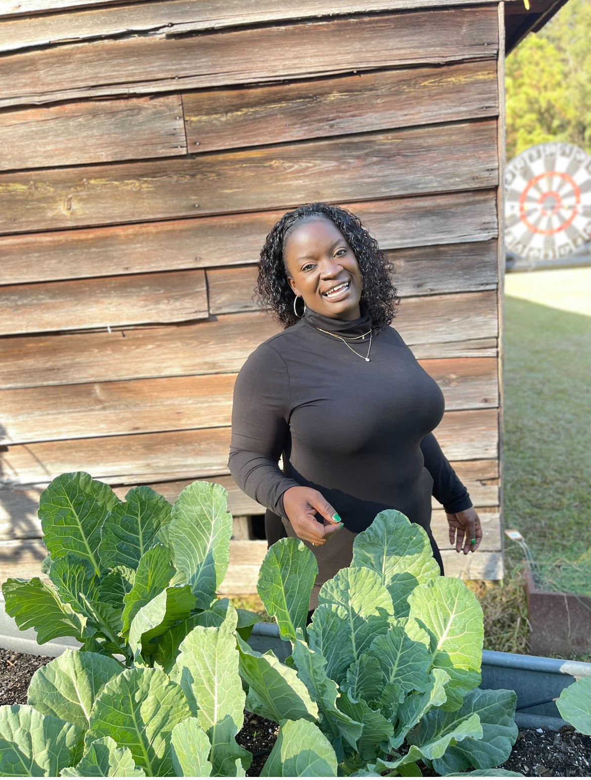Erica Plants standing behind a raised bed of broad green leaves.