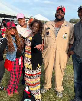 A group of people smiling together at an outdoor gathering.