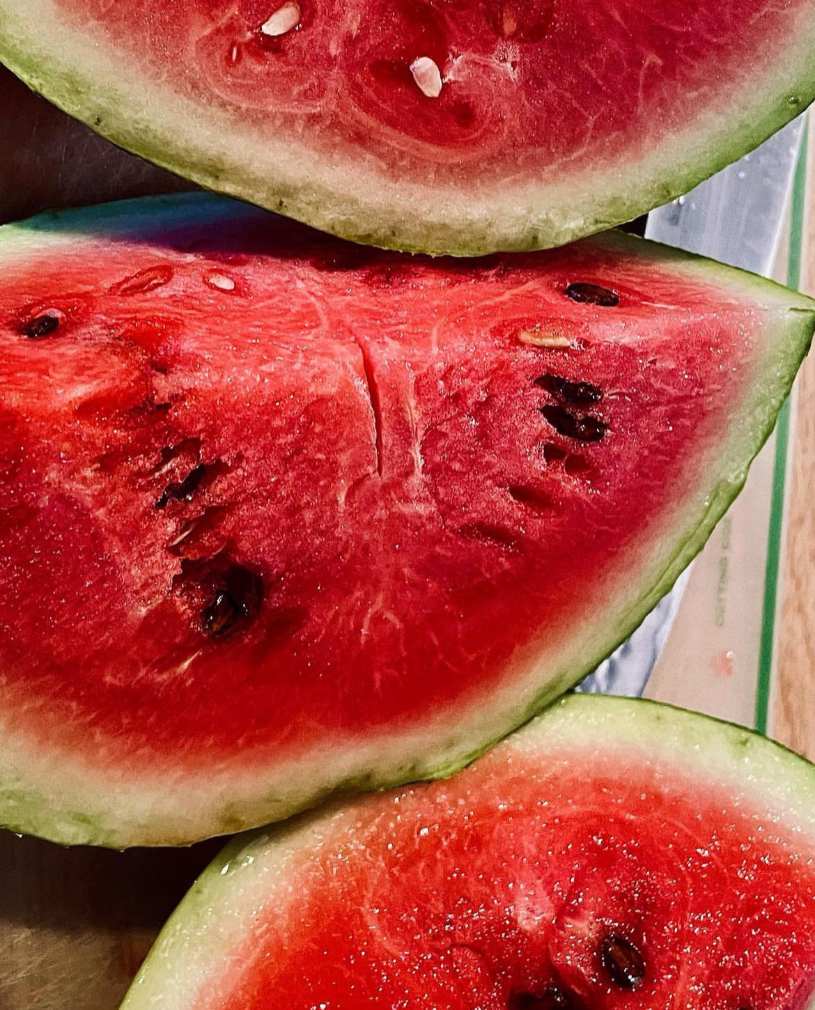 Red watermelon wedges with black seeds and pale green rind.