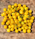 Small round Gold Nugget tomatoes piled on a wooden surface — from BlackOwnedSeeds.com.
