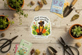 Sticker illistration of a person sitting in nature with text 'plant something heal something' and a website URL.