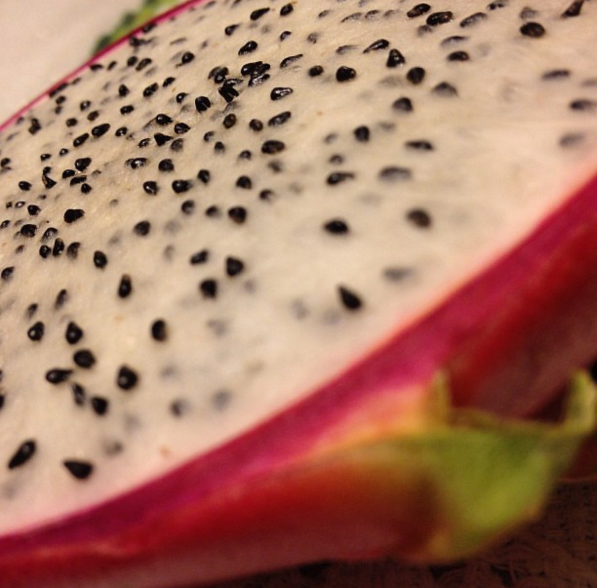 Cut dragon fruit showing white flesh densely dotted with black seeds.
