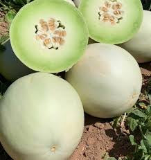 Whole pale honeydew melons beneath cut halves showing green flesh and seeds.