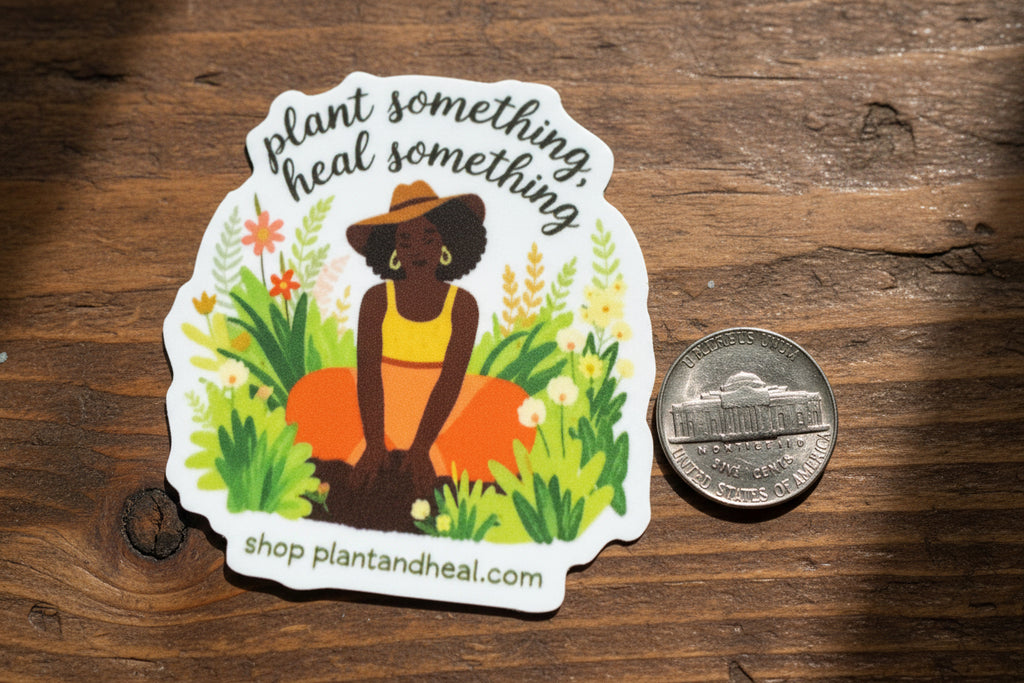 Sticker with a design of a person holding plants and text 'Plant something, heal something' on a brown wooden table background.