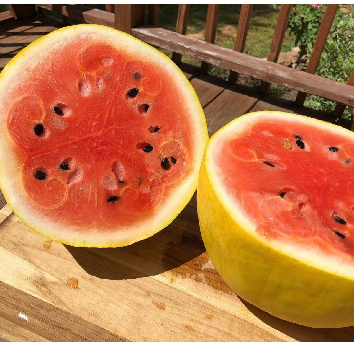 Two halves of a yellow-rind watermelon on a wooden table.