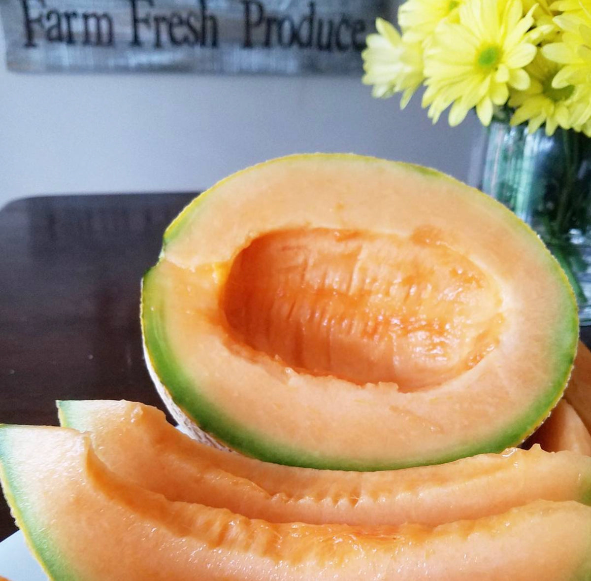 An orange-fleshed Honey Rock melon half with slices arranged below it — from BlackOwnedSeeds.com.