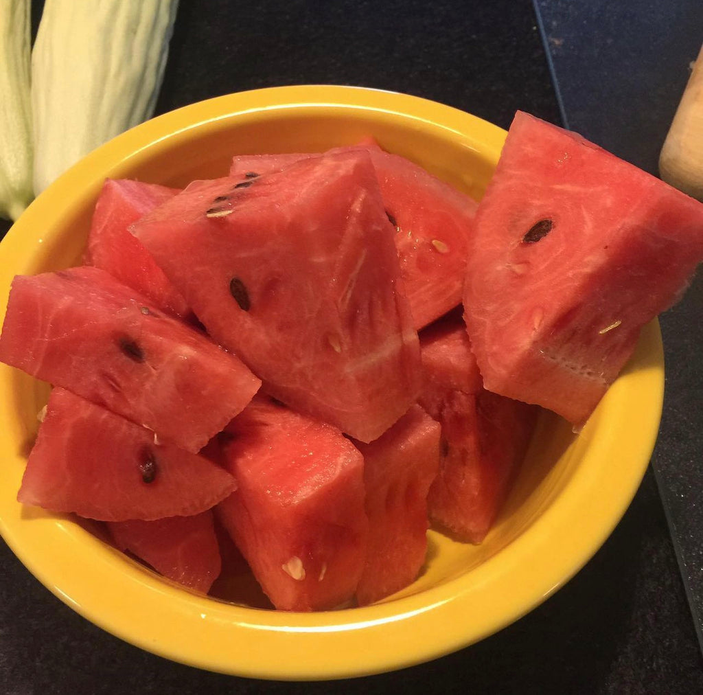 Chunks of red watermelon piled in a yellow bowl.