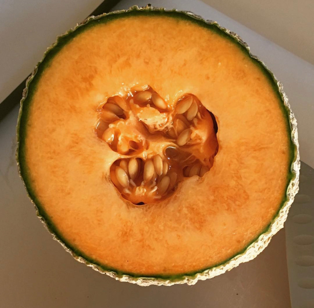 A melon cut across the middle, showing orange flesh and a central seed cavity.