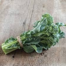 A tied bunch of harvested broccoli shoots on a wooden surface.