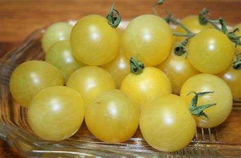 A glass bowl filled with pale yellow White Cherry tomatoes.