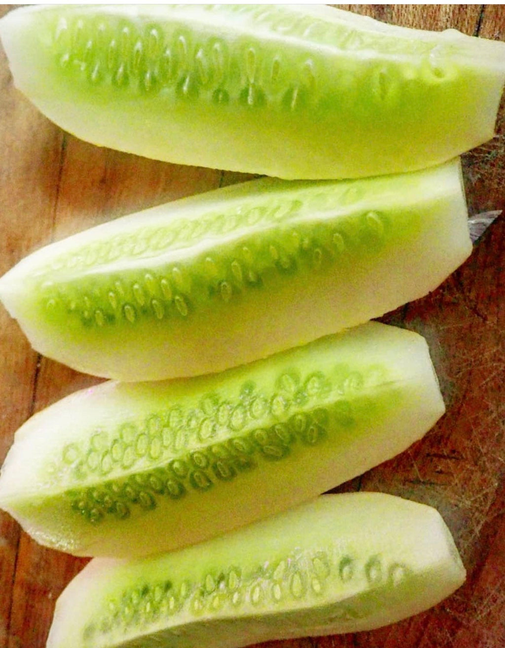 Pale cucumbers sliced lengthwise to reveal green flesh and seed cavities.