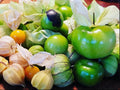 Green tomatillos and purple-tinged fruit surrounded by papery husks — from BlackOwnedSeeds.com.