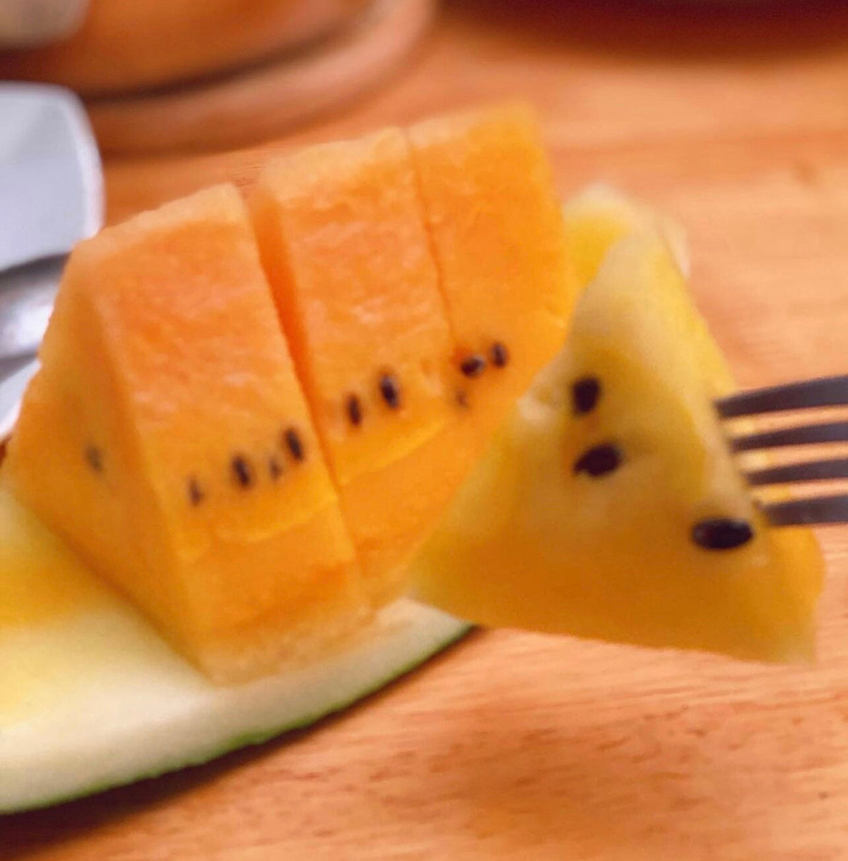 Orange watermelon flesh cut into cubes while still resting on its rind — from BlackOwnedSeeds.com.